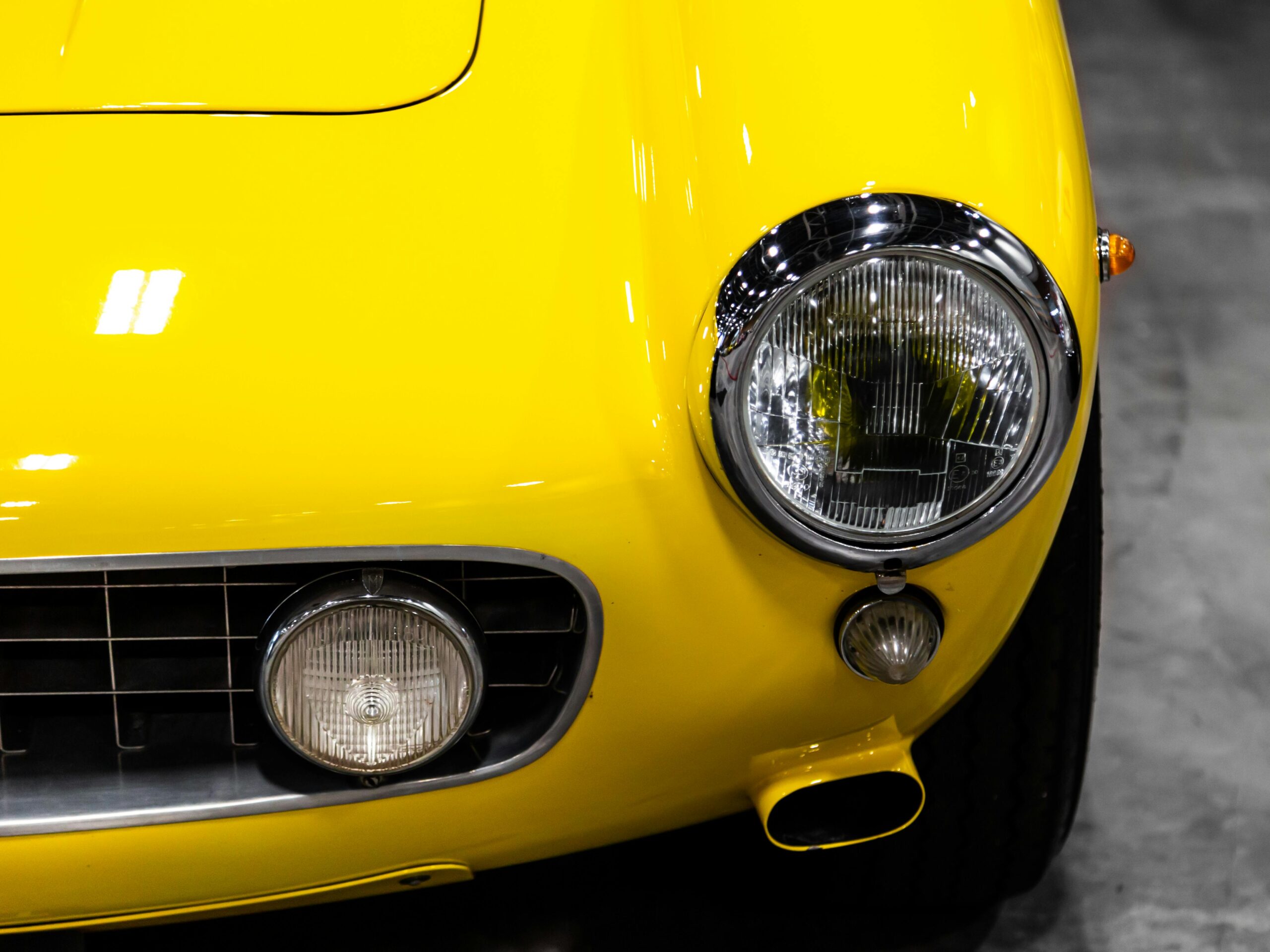the front end of a yellow classic car with a round headlight similar to a shelby cobra